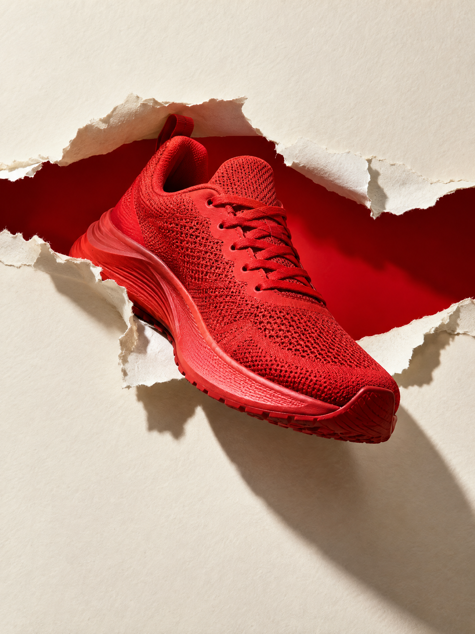 Red sneaker emerging through a paper tear product effect